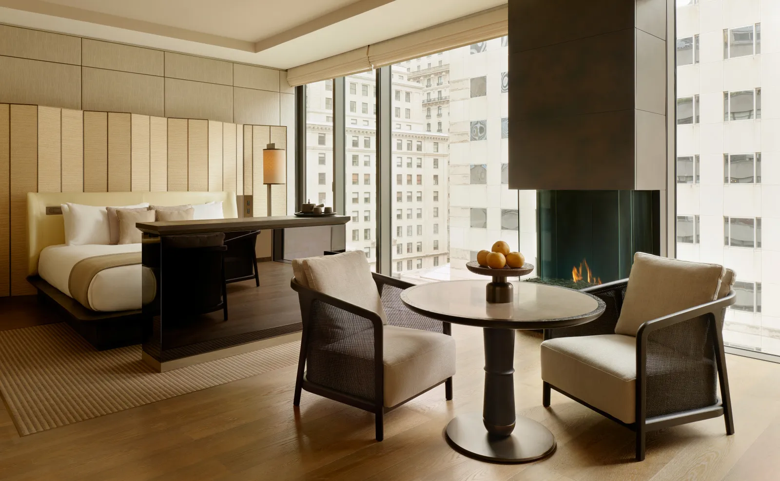 Premier Suite at Aman New York with bed, seating area, and floor-to-ceiling windows overlooking the city.