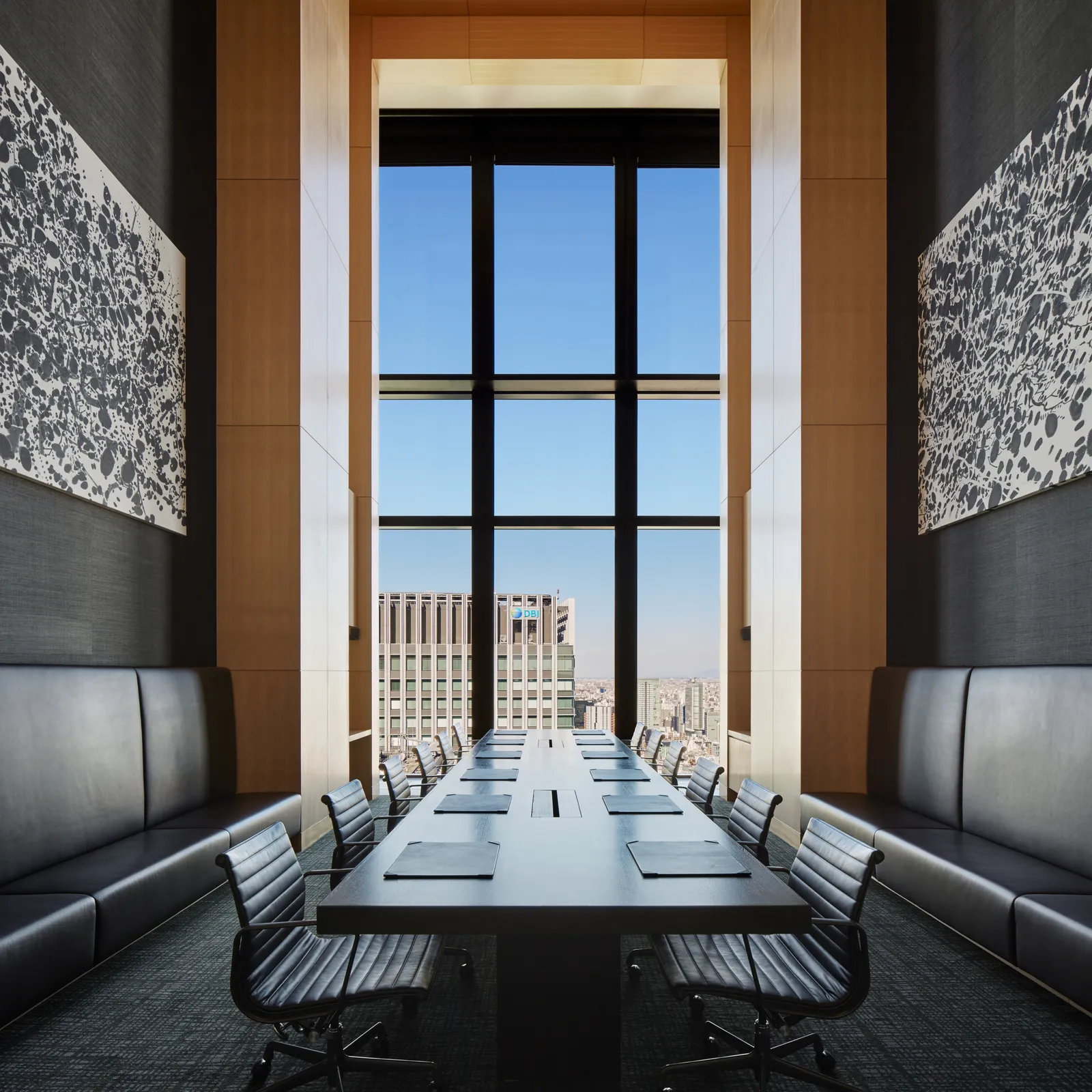 The boardroom: a long table with black leather chairs before a window 2 storeys high.