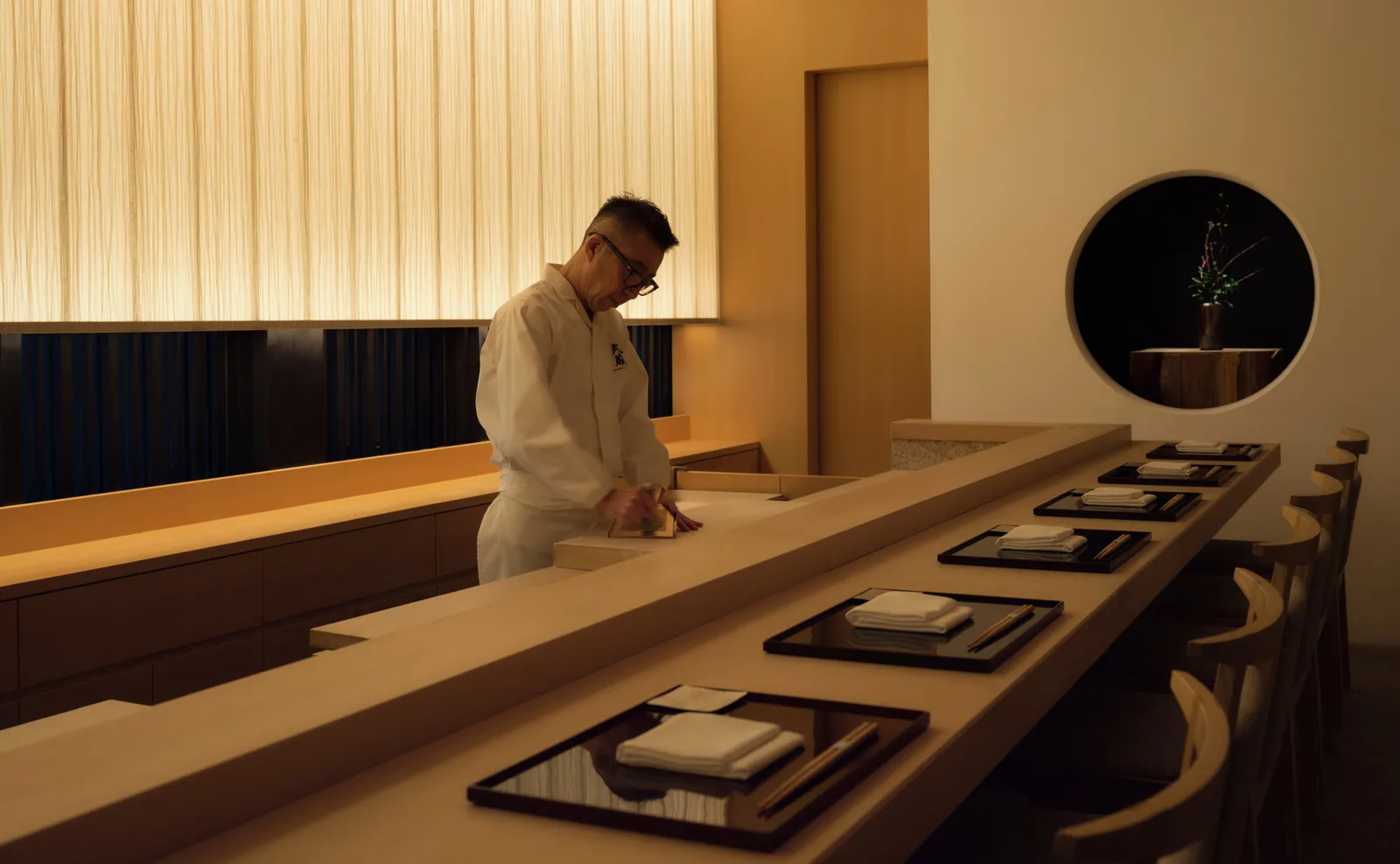 Musashi by Aman’s hinoki cypress counter, laid with black trays, the chef at work behind it.