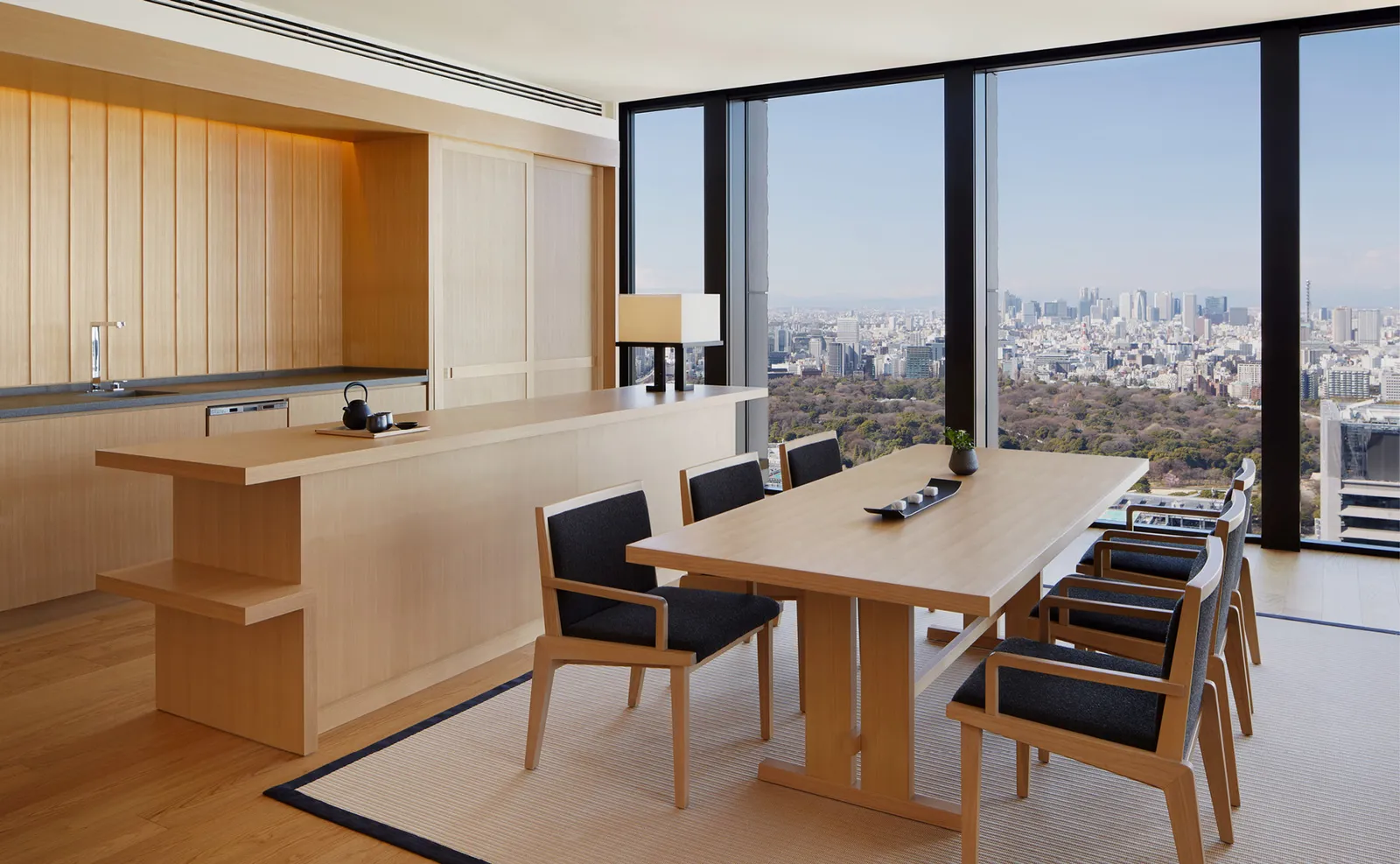 The Aman Suite’s dining room, with its table for 6, the wooden kitchen and the windows onto the gardens and the city.