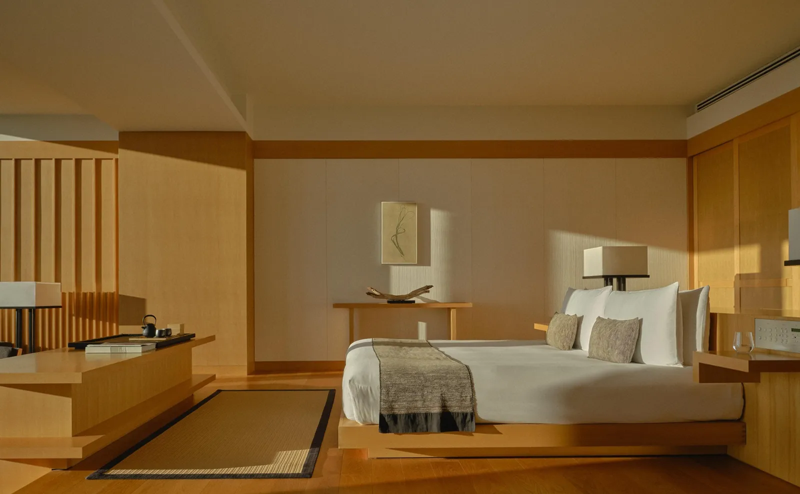 A Grand Suite bedroom, with the low bed, pale wood walls and the sunken seat on the left.