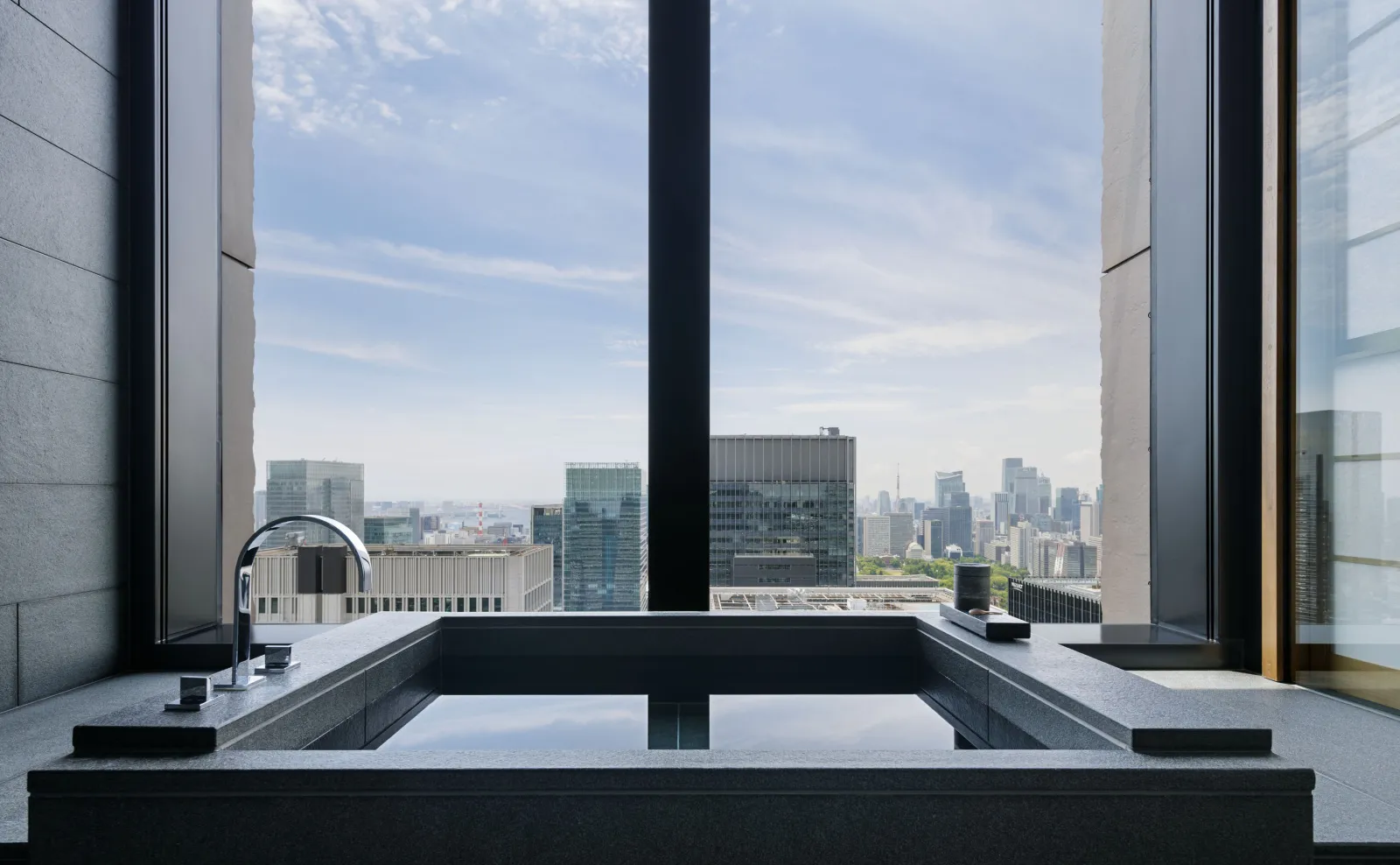 A Panorama Suite bathroom: the dark stone furo tub against the window, above the towers.