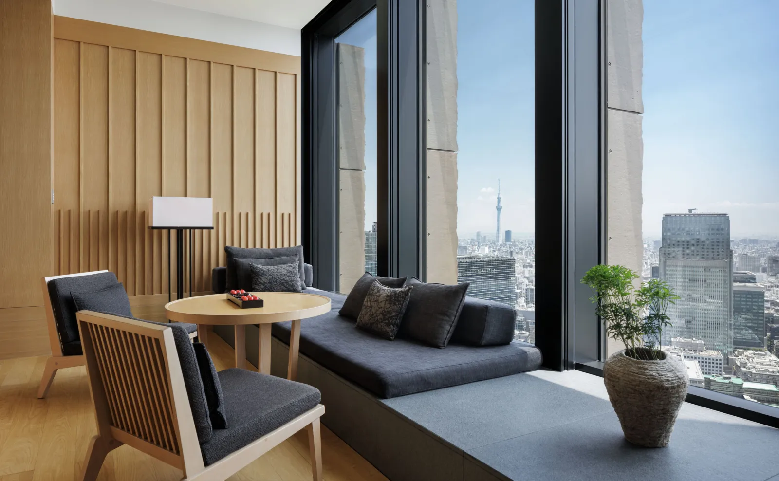 The window corner of a Tokyo Suite, with the sofa, the round table and the Skytree in the distance.
