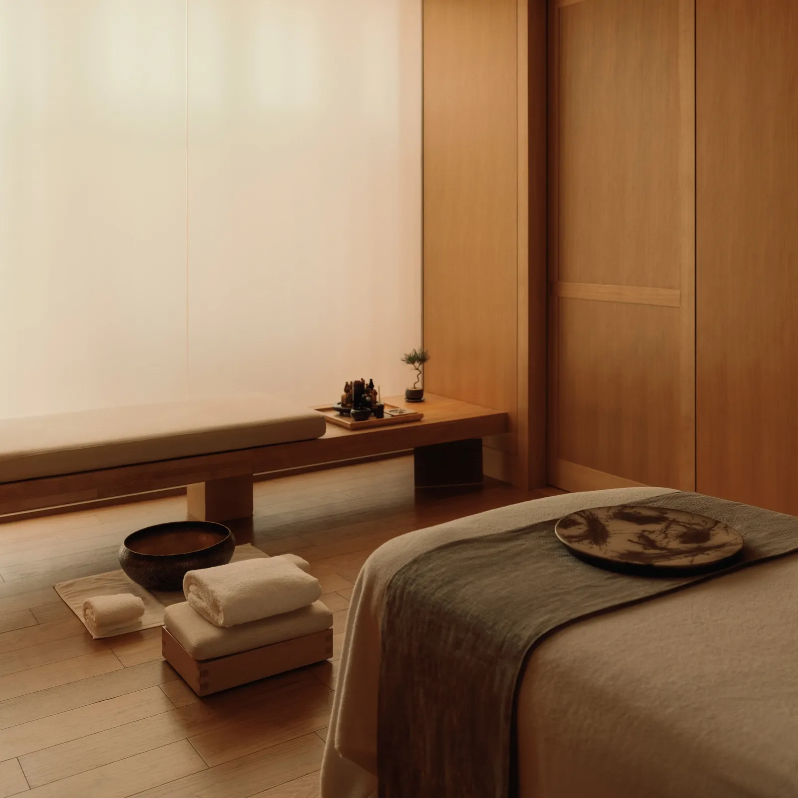 A spa treatment room, with the couch, the low wooden bench and folded towels.