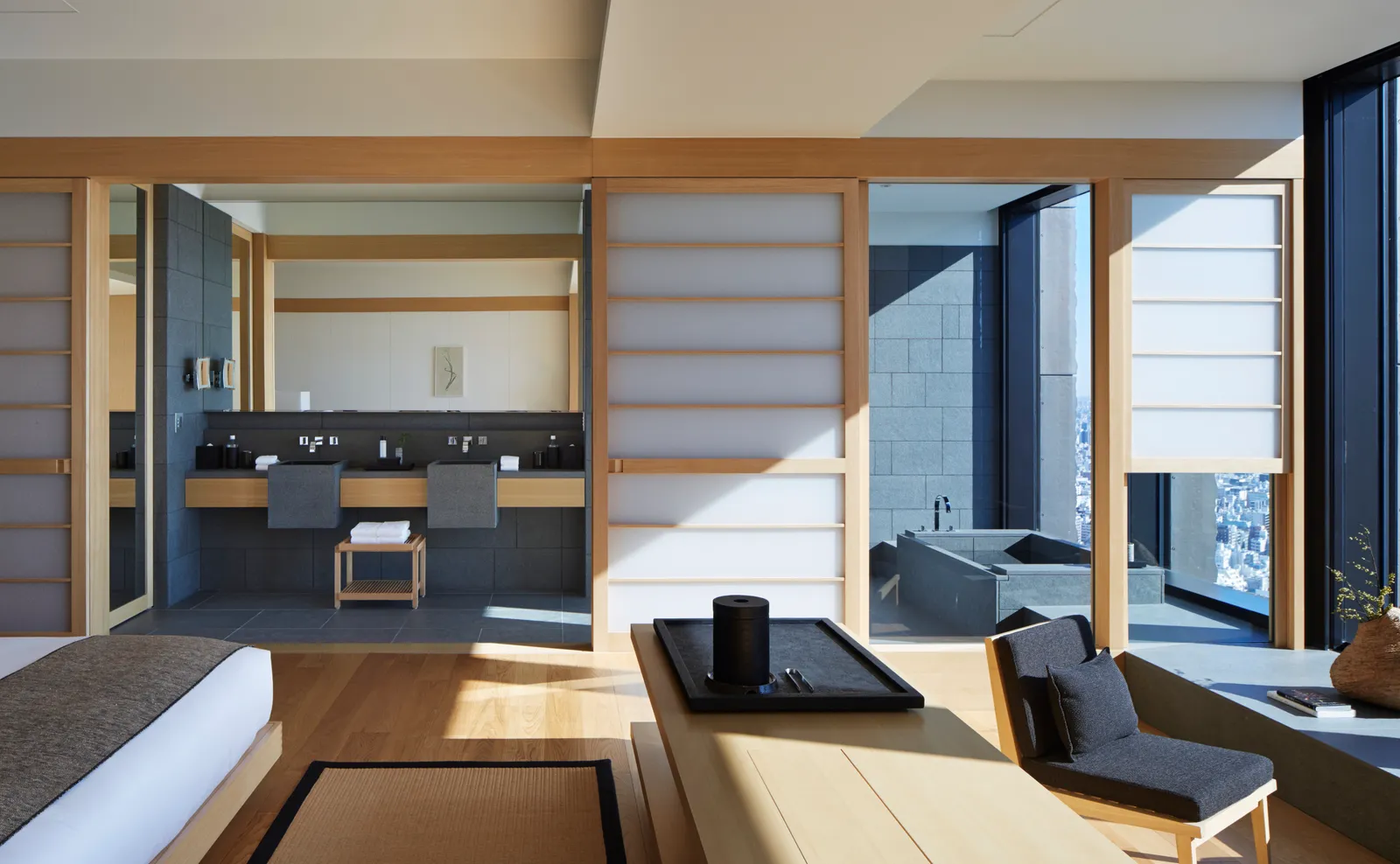 The Aman Suite: the bed and the seat in front, the shoji open onto the bathroom with its stone tub beside the window.