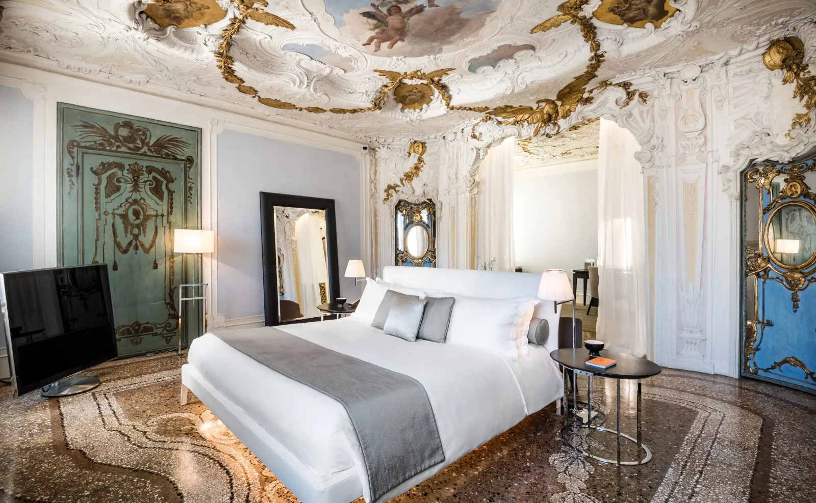 The Alcova Tiepolo Suite bedroom: the stucco and fresco ceiling, the green painted doors and the white bed.