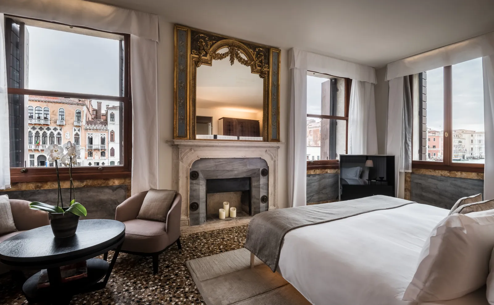 The Grand Canal Suite bedroom: the bed, the fireplace with its gilded mirror and 2 windows onto the Grand Canal.