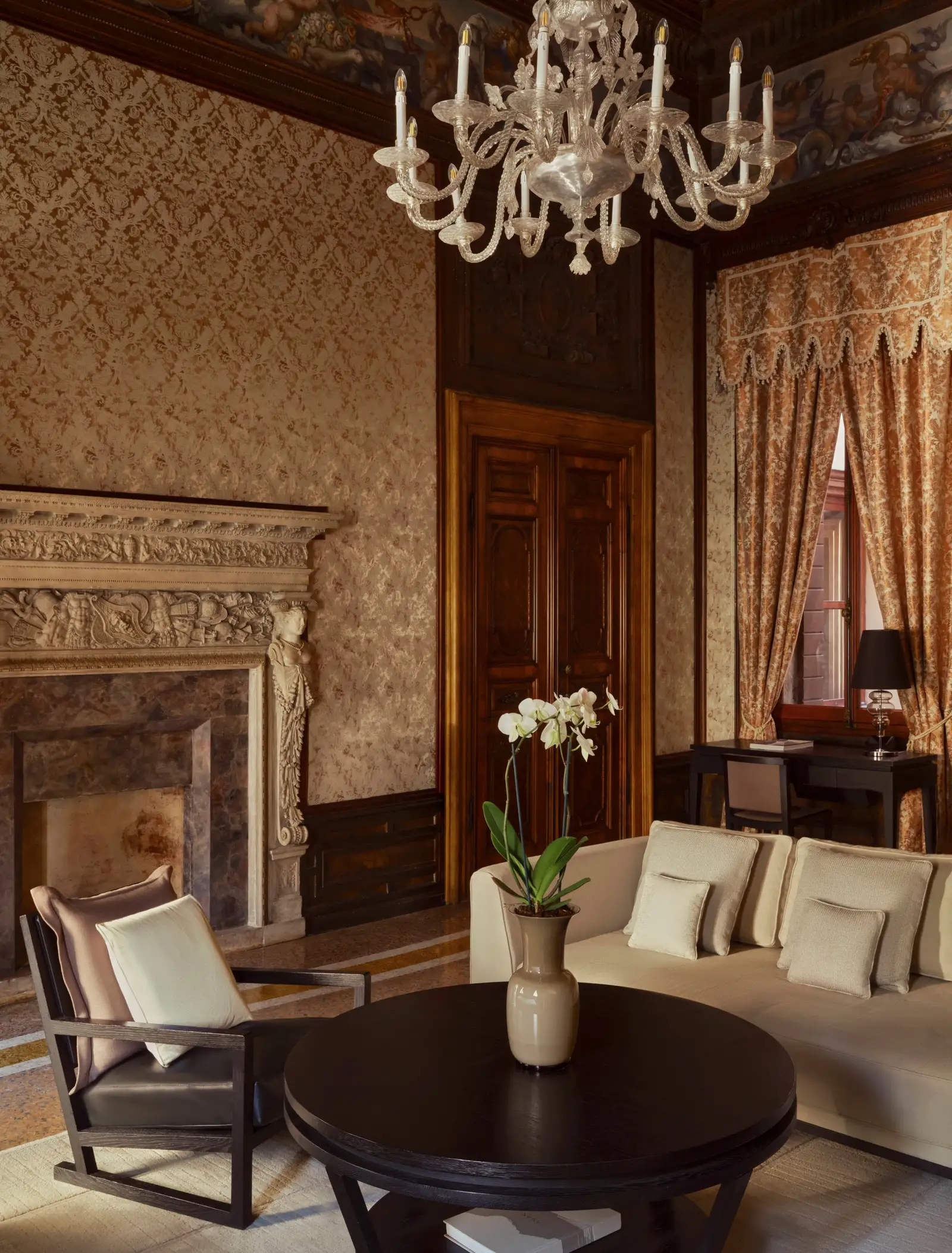 The Sansovino Stanza: the 16th-century stone fireplace, the glass chandelier, silk walls and timber doors.