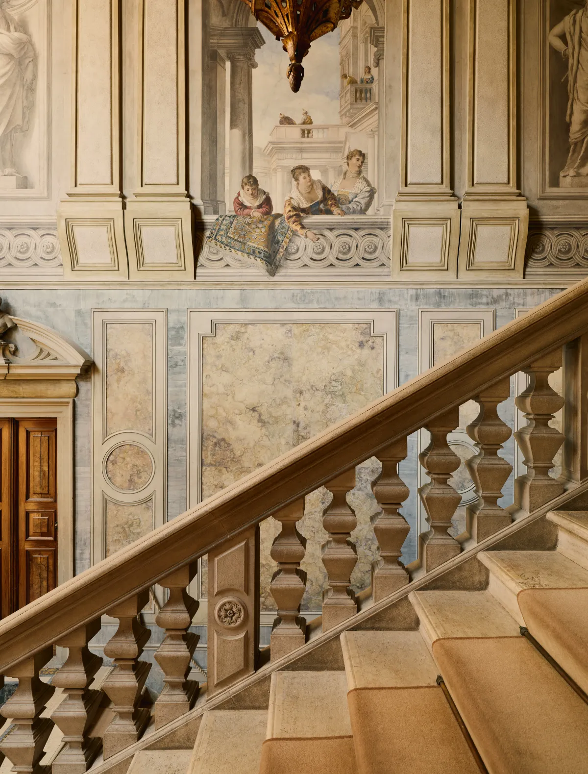 The palazzo’s great staircase: the stone balustrade climbing beneath the frescoed walls.
