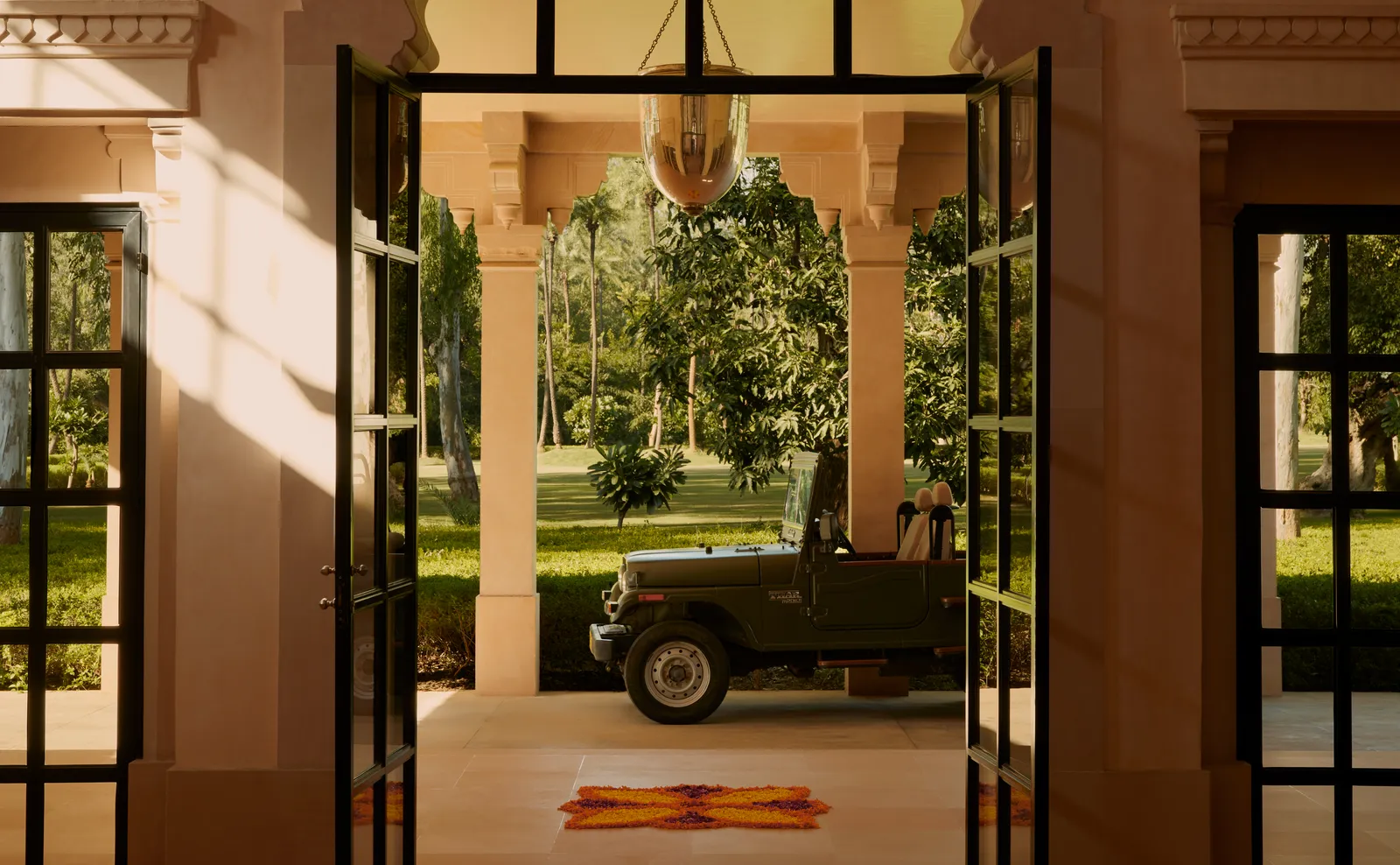 A jeep parked under the entrance portico, seen through the lobby’s open doors