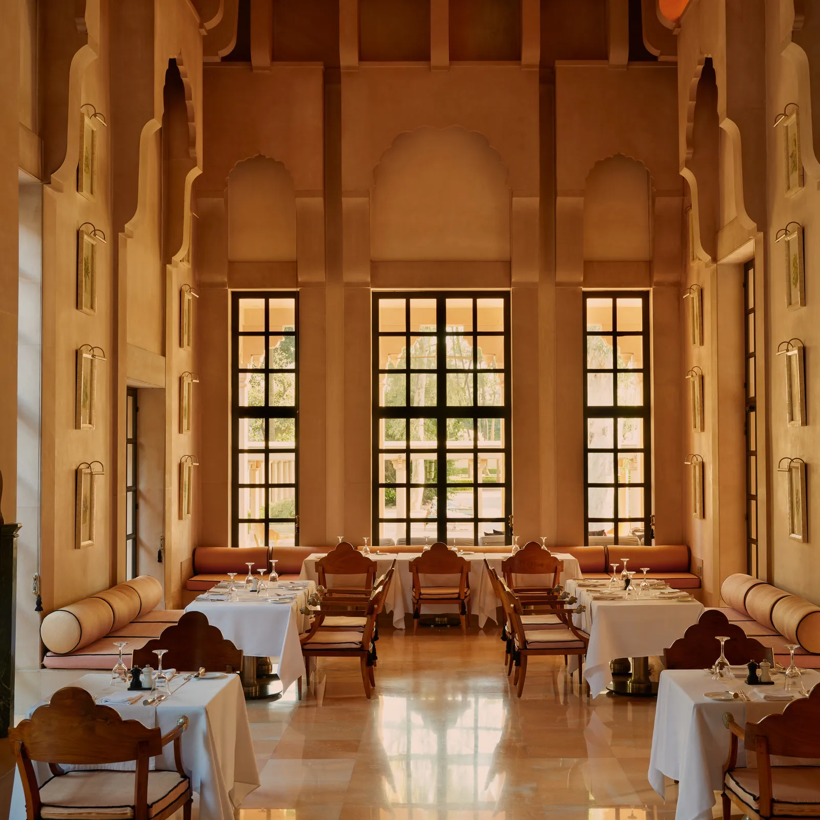 The restaurant’s dining room, with tall arched windows and tables laid in white