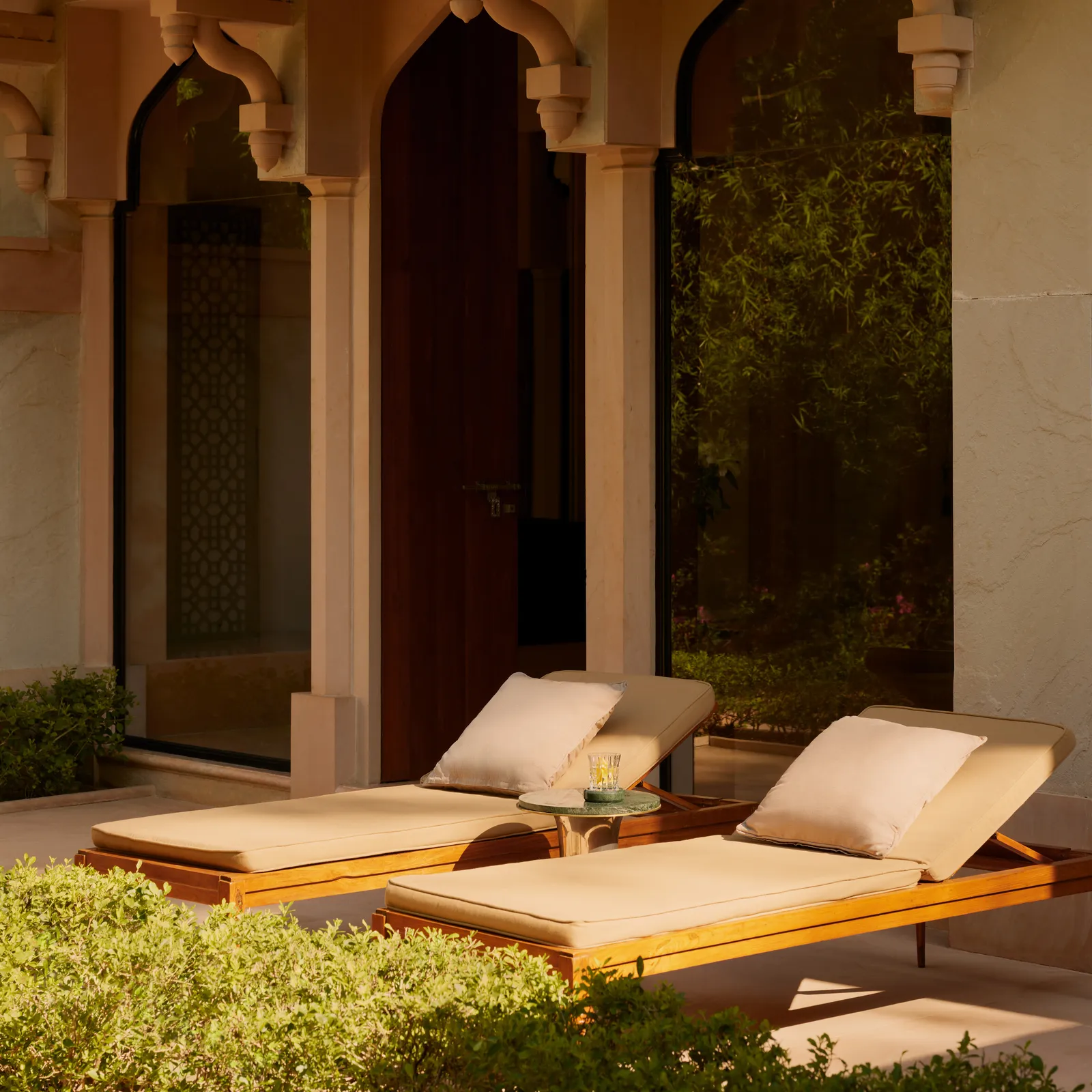 A Garden Haveli Suite’s terrace with 2 cushioned loungers above the garden