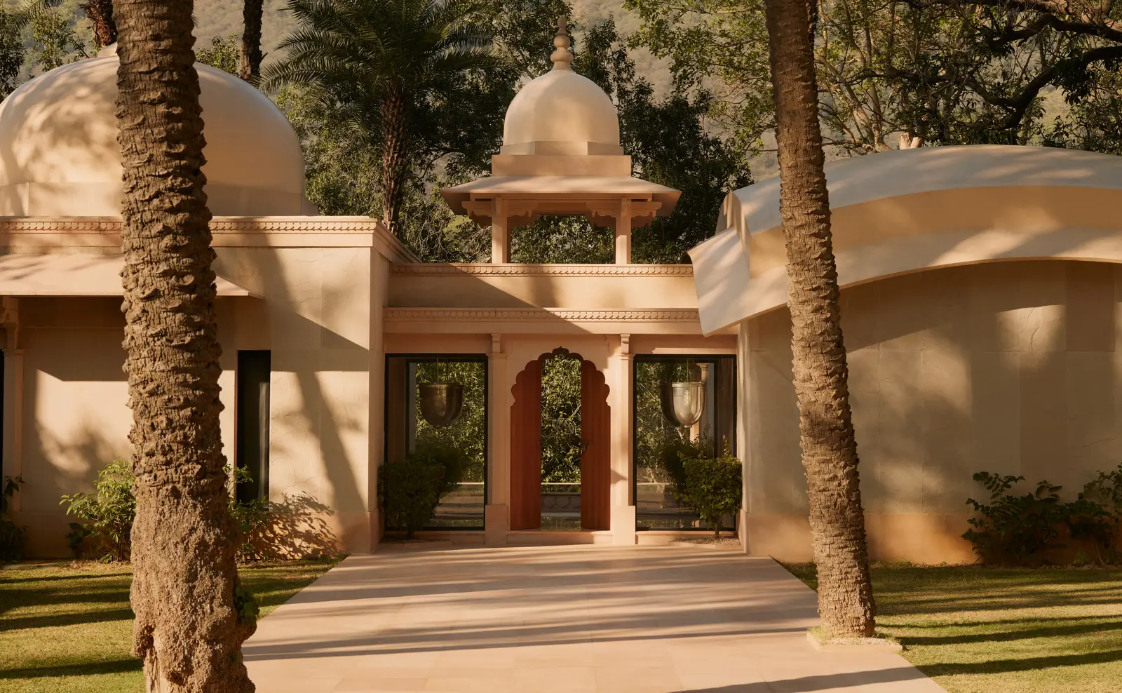 A Pool Pavilion with its sand-coloured domes and arched doors among palms