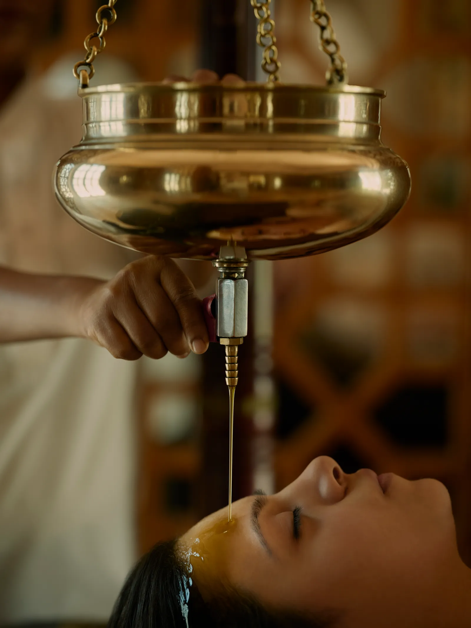 Warm oil falling onto a guest’s forehead during a shirodhara