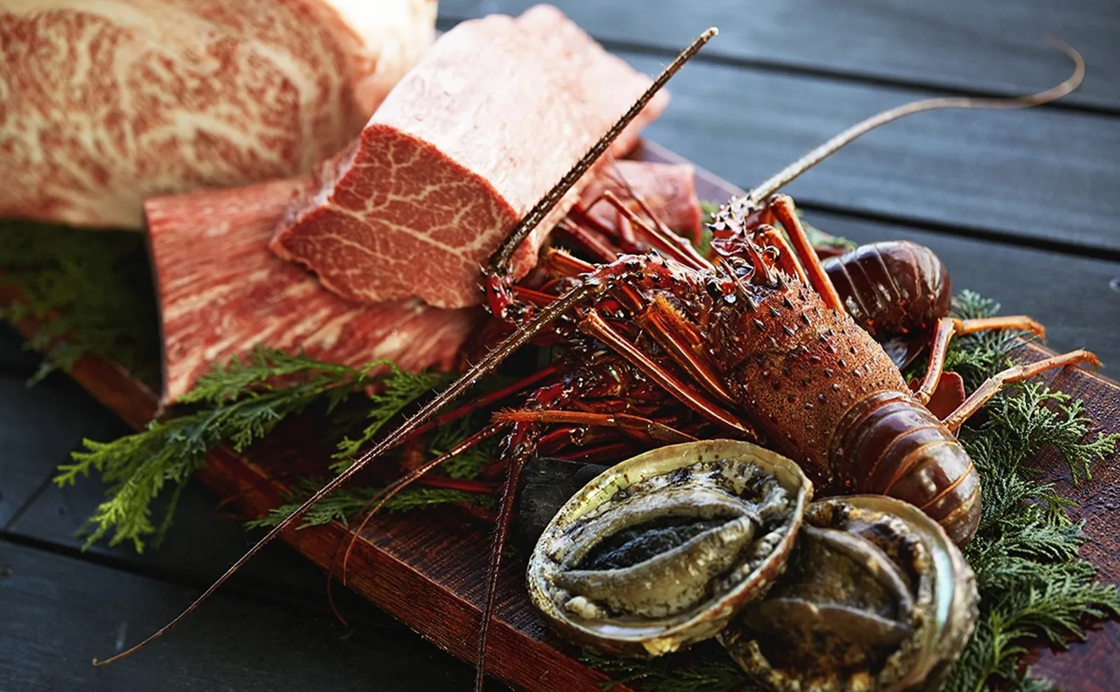 Matsusaka beef, a spiny lobster and abalone on a board with cedar sprigs