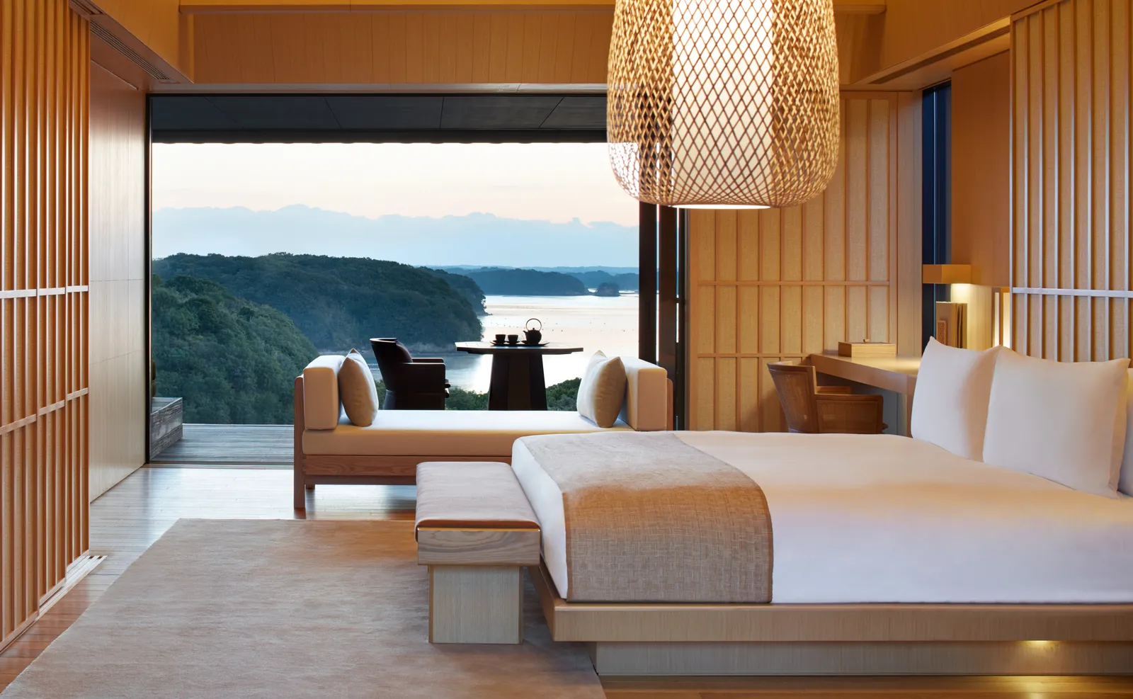 A bed and a veranda opening wide onto the bay at dusk