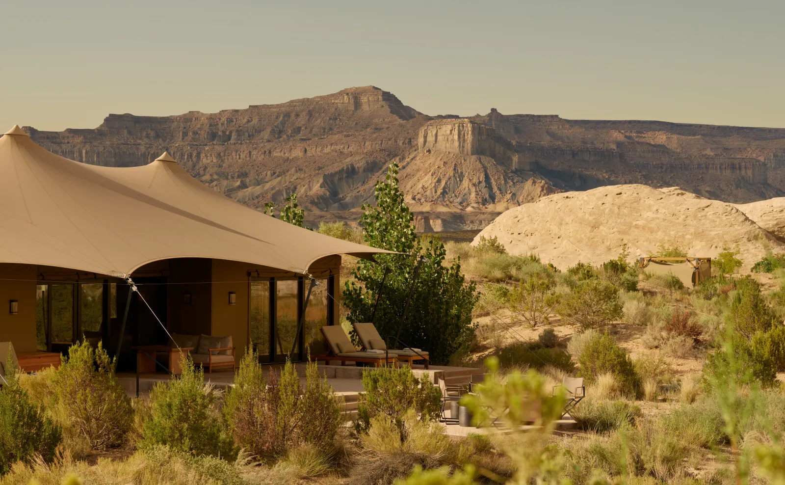 A tented pavilion at Camp Sarika: pale canvas stretched above glass walls, loungers outside and the plateau in the distance.