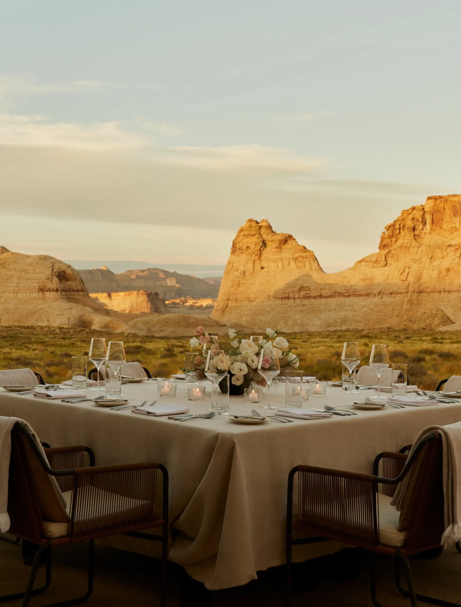 A table laid with white flowers at the Desert Lounge, facing mesas lit by the sunset.
