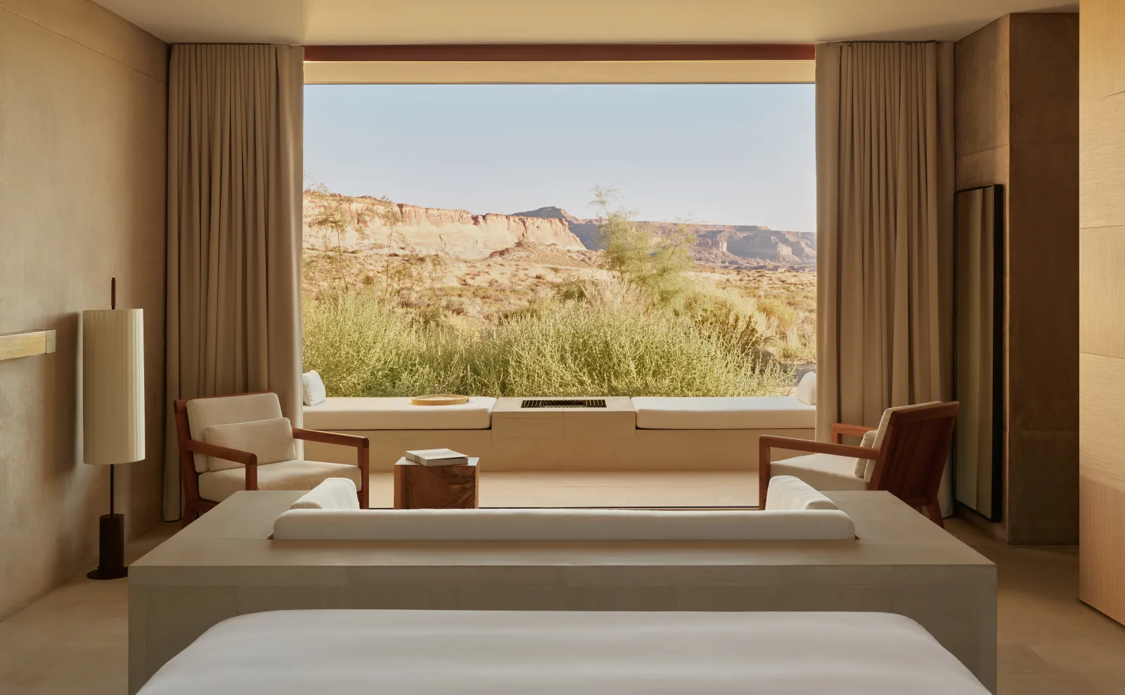A Desert Suite: the bed in front, the sofa and 2 armchairs before the wide window onto the dunes.