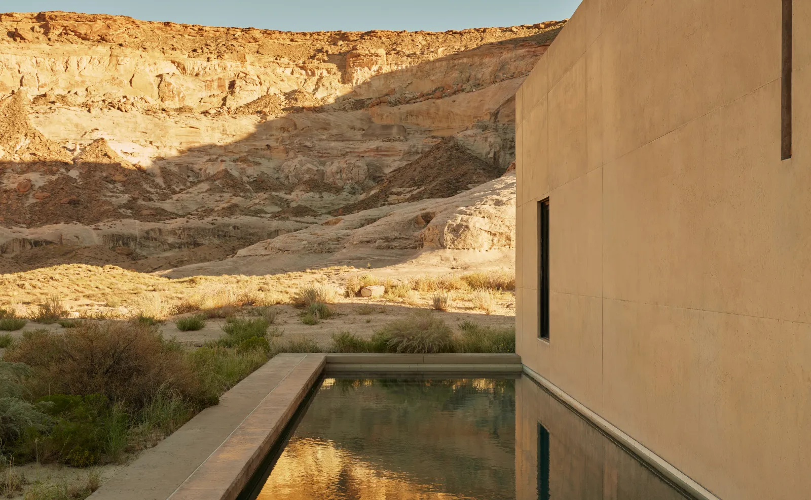 A Girijaala Suite’s long pool running along the concrete wall, the rock ridge lit by the sun.