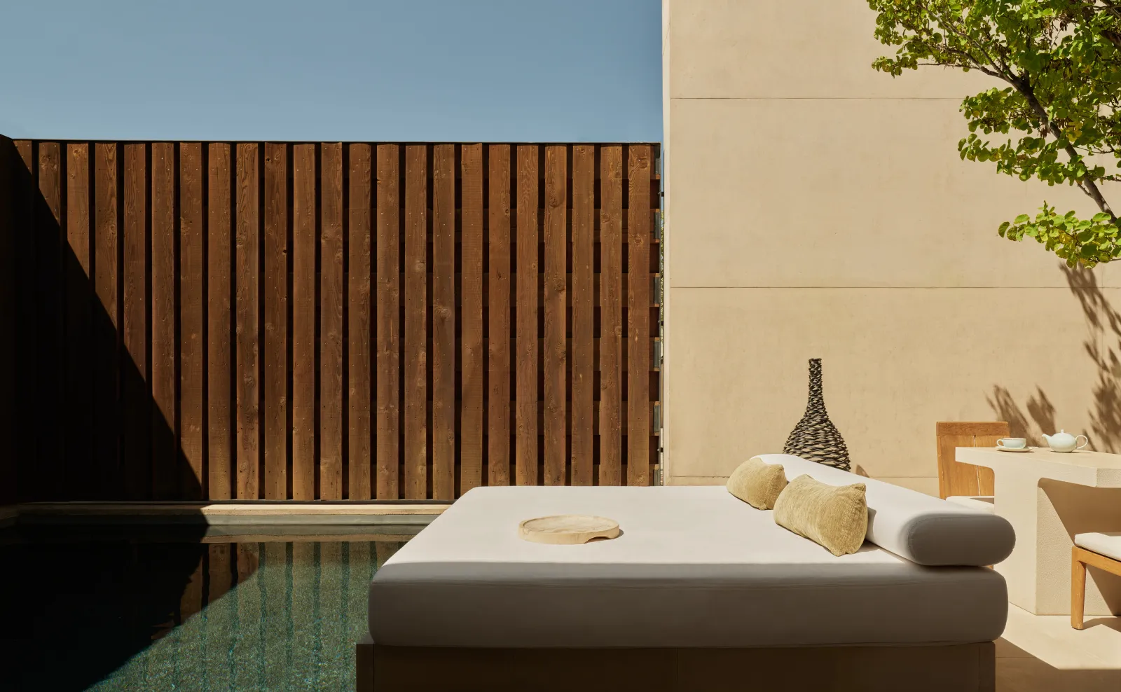 A Mesa Pool Suite: the daybed beside the private pool, against a wall of dark timber slats.