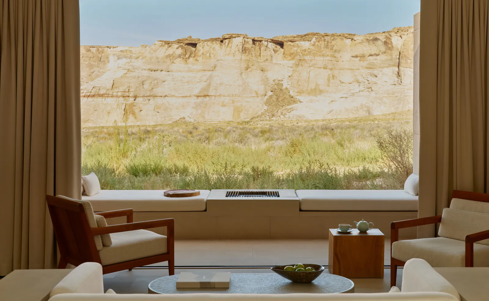 A Mesa Suite’s sitting area, 2 wooden armchairs and a low table before the window onto the pale cliff.