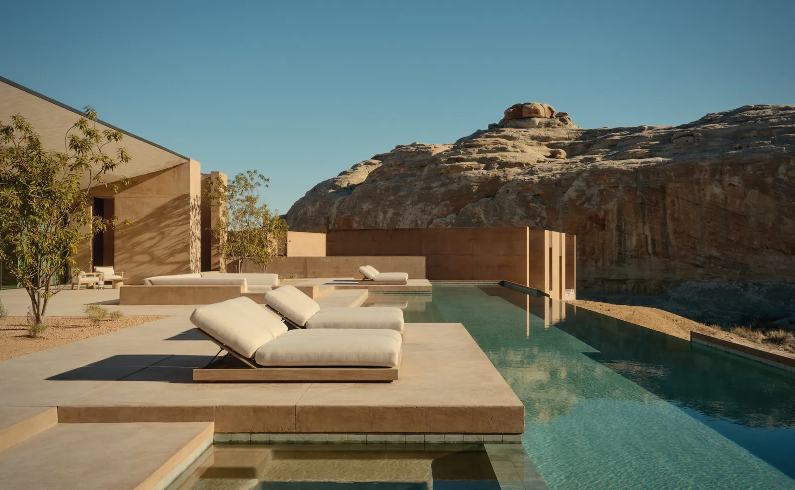 The 6-bedroom villa’s pool: 2 loungers on a stone platform and a dome of rock behind the wall.