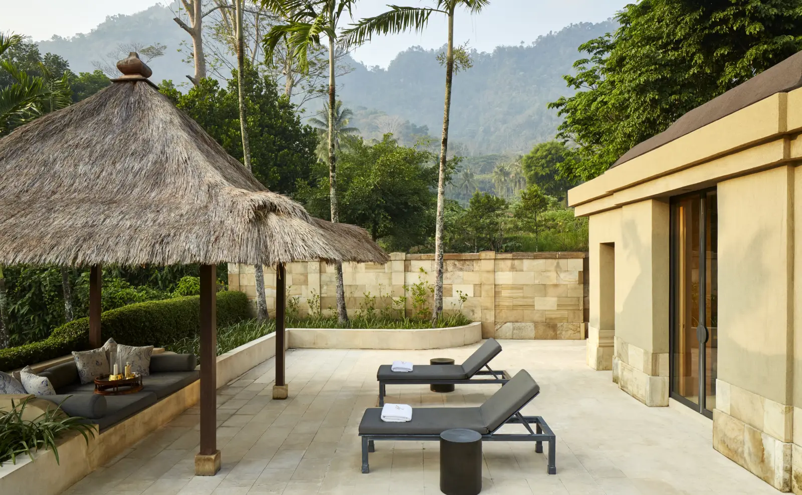 A terrace with 2 loungers and a balé, wooded hills behind
