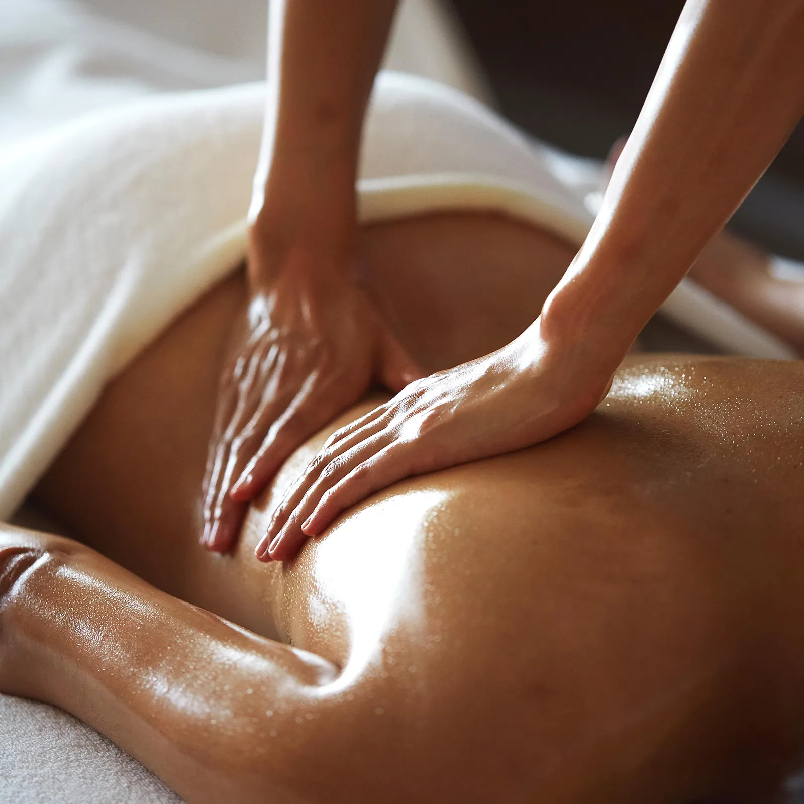 A therapist’s hands working oil into a guest’s back