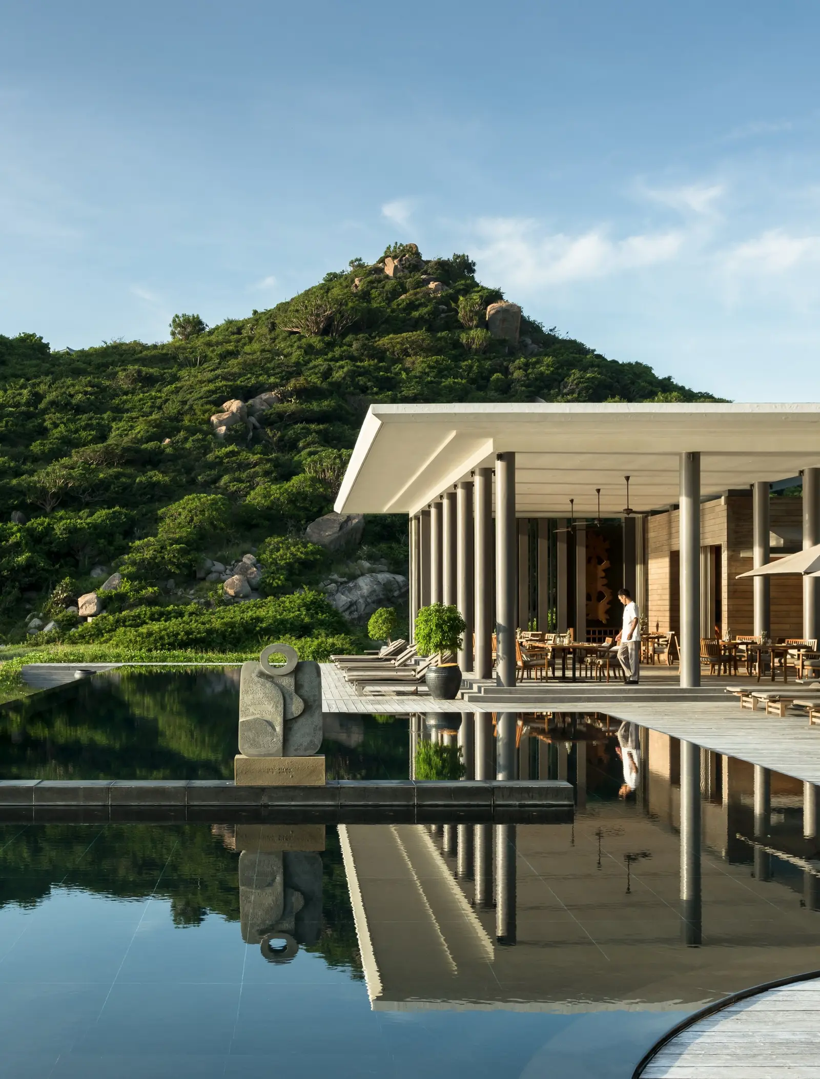 The Beach Club reflected in its pool, under the hill