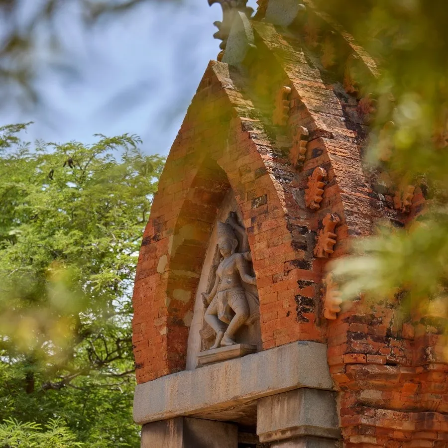 One of the brick Cham towers, its carving above the doorway, through the leaves