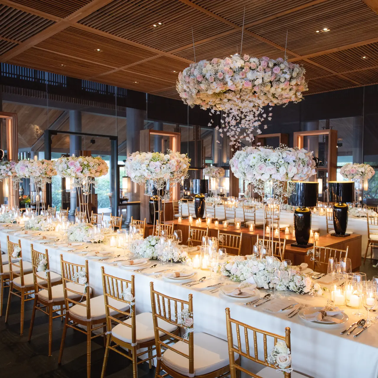 The Glass Hall set for a dinner: a long table of white flowers under a floral chandelier