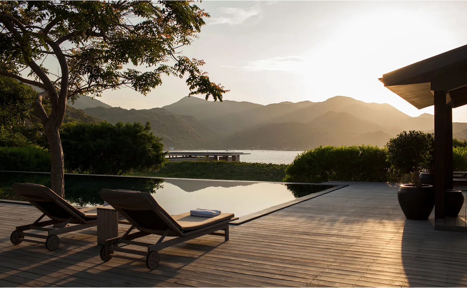 The Five-Bedroom Bay Pool Residence deck with loungers and pool, the bay at sunset