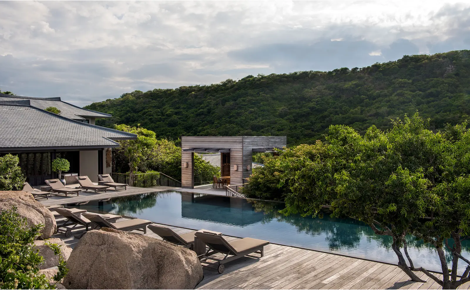 The Five-Bedroom Pool Residence’s pool among the boulders, with loungers and pavilions