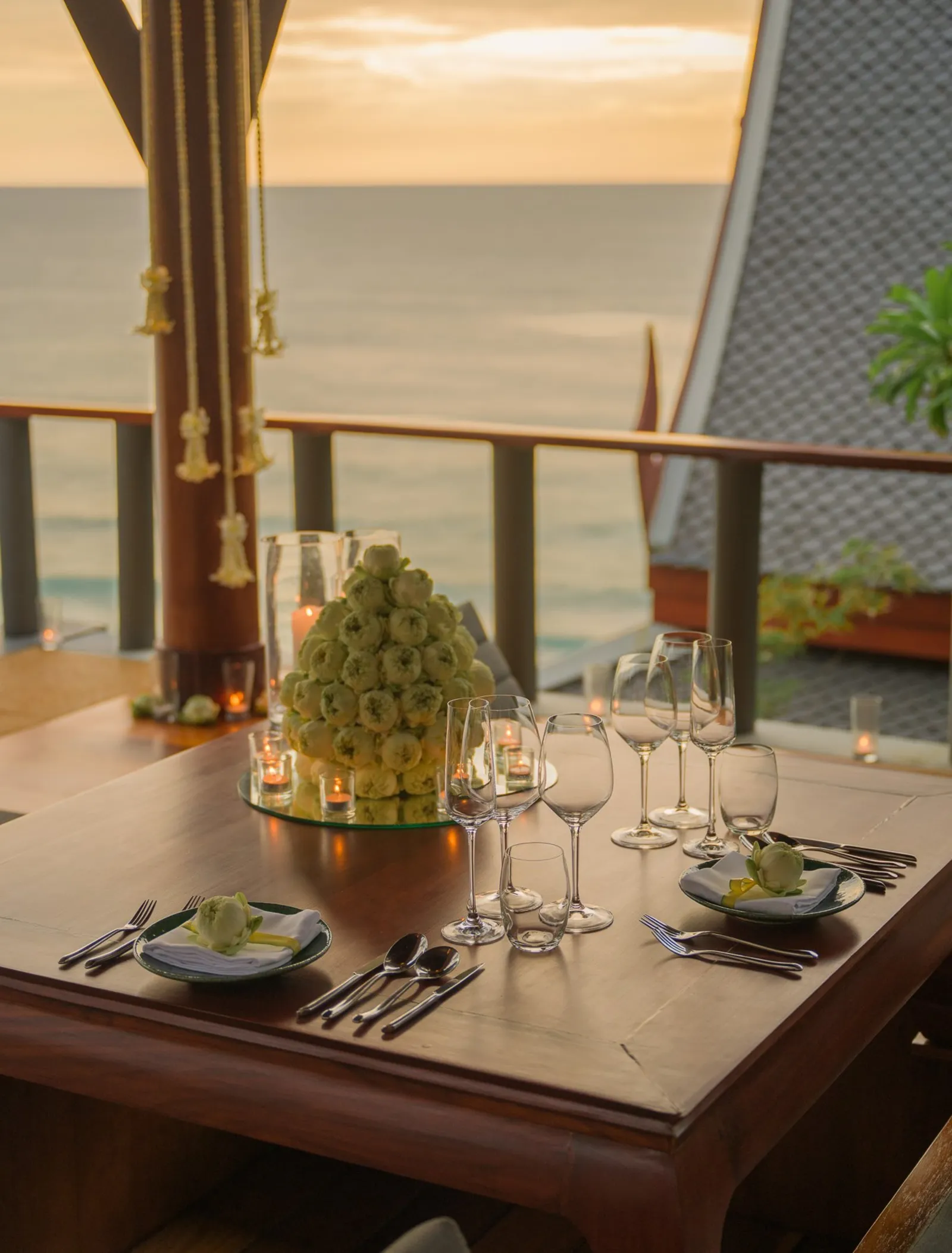 A private dining pavilion laid for a Royal Thai dinner, the sea at sunset