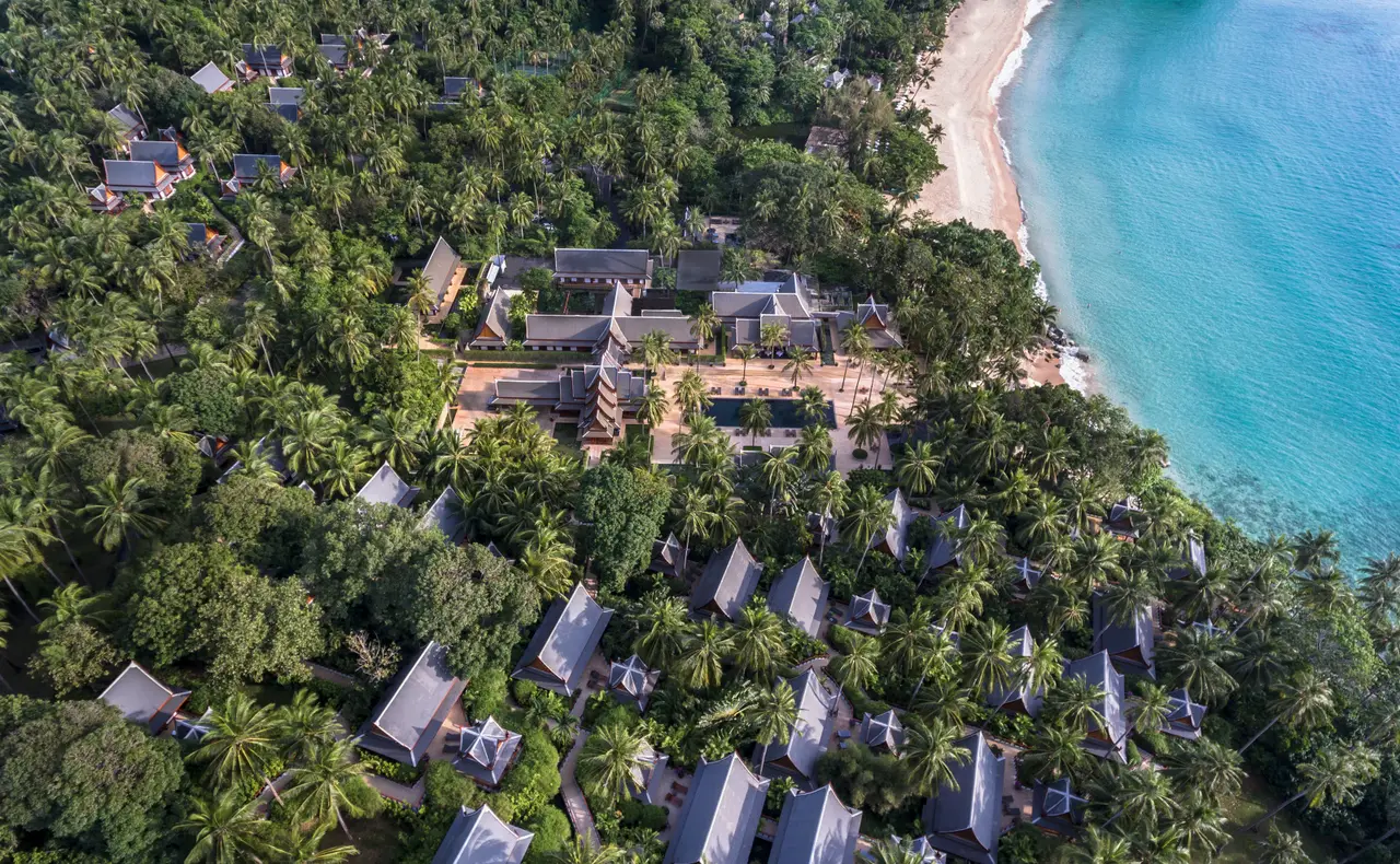 The headland from above: pointed grey roofs among the palms and the white curve of Pansea Beach