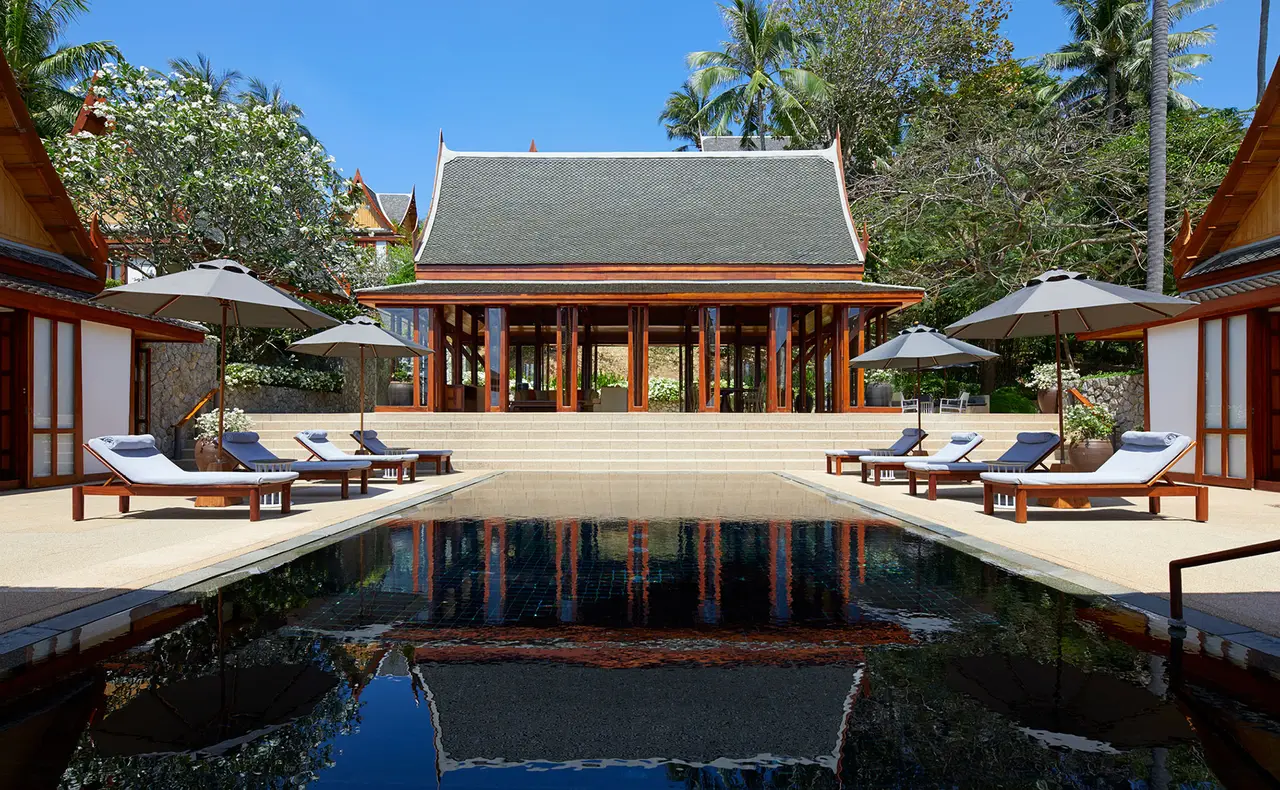 A villa pool with a teak pavilion and parasols