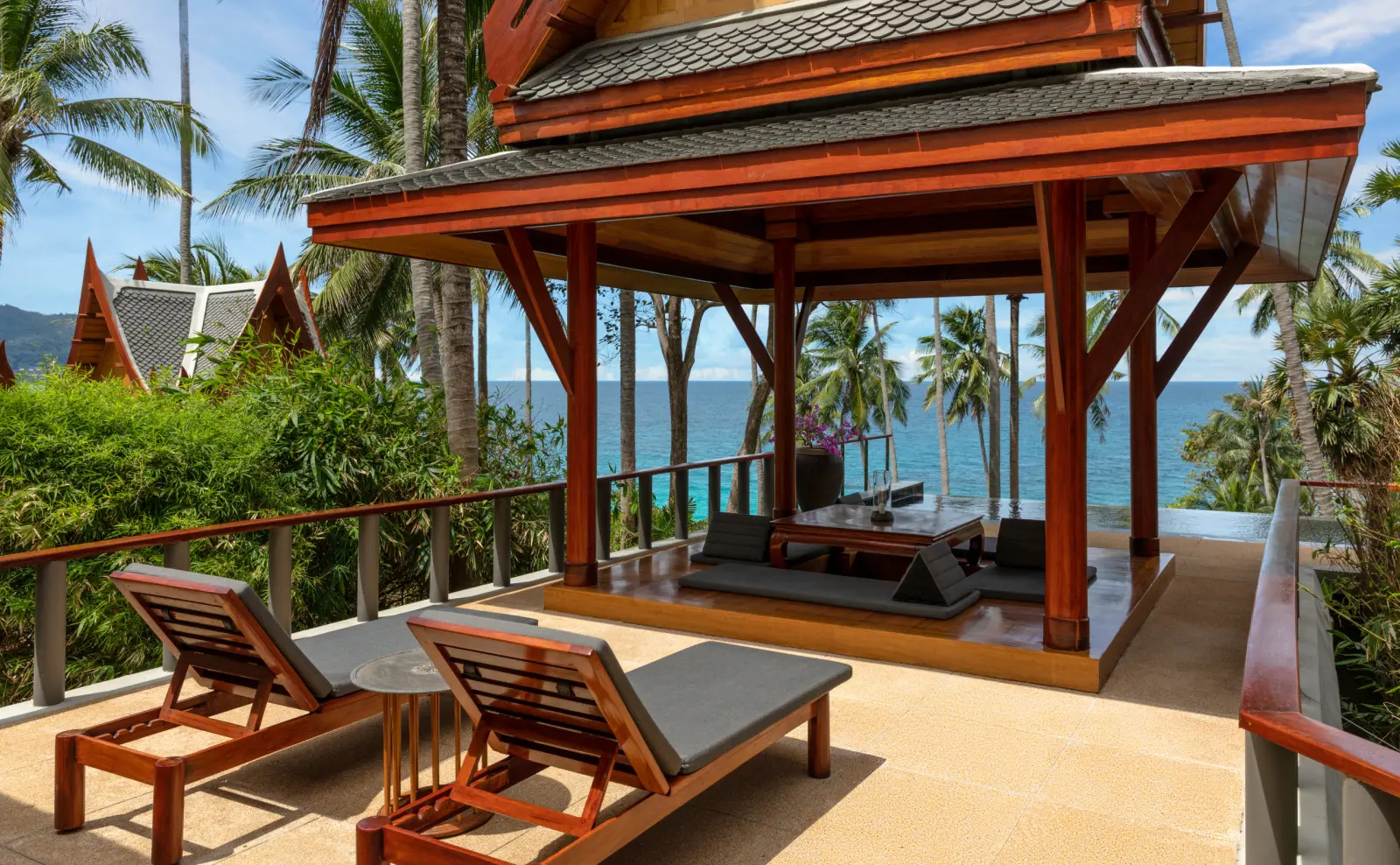 An Ocean Pool Pavilion’s sala and loungers, the sea and a headland behind