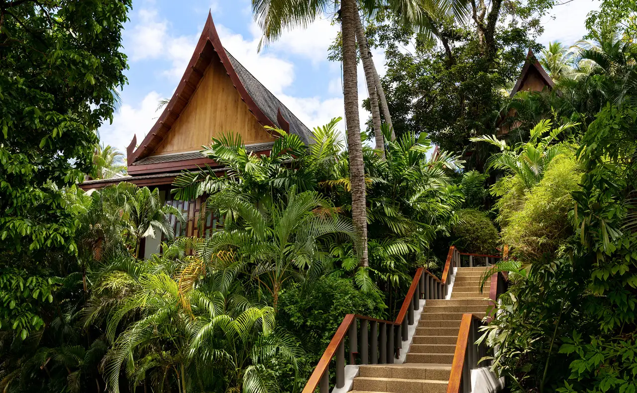 A Pavilion with its golden peaked roof among palms, steps leading up to it