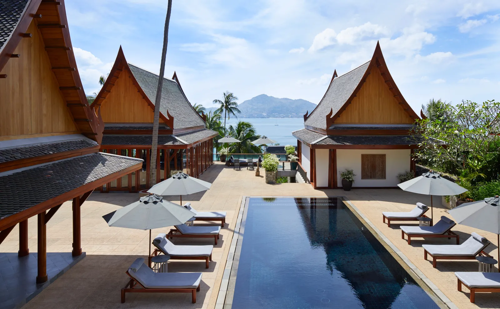Thai pavilions at the head of a villa pool lined with parasols