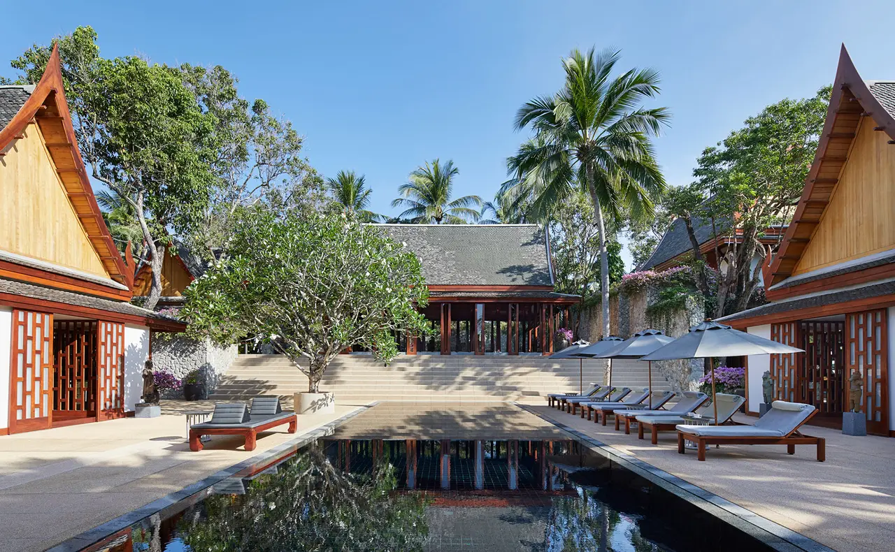 A villa pool among palms with pavilions around it