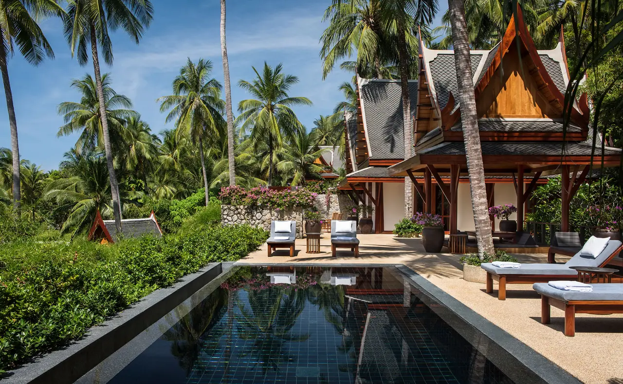 The long pool of the Two-Bedroom Pool Pavilion with loungers and a teak pavilion