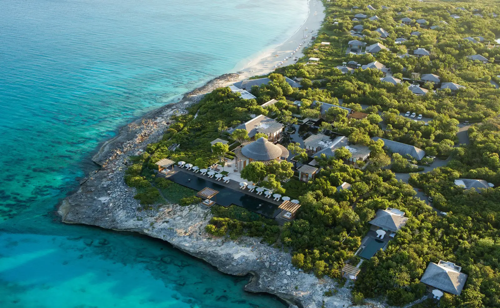 Amanyara from above: pavilion roofs in the scrub, the rocky shore and turquoise water as far as the white beach.