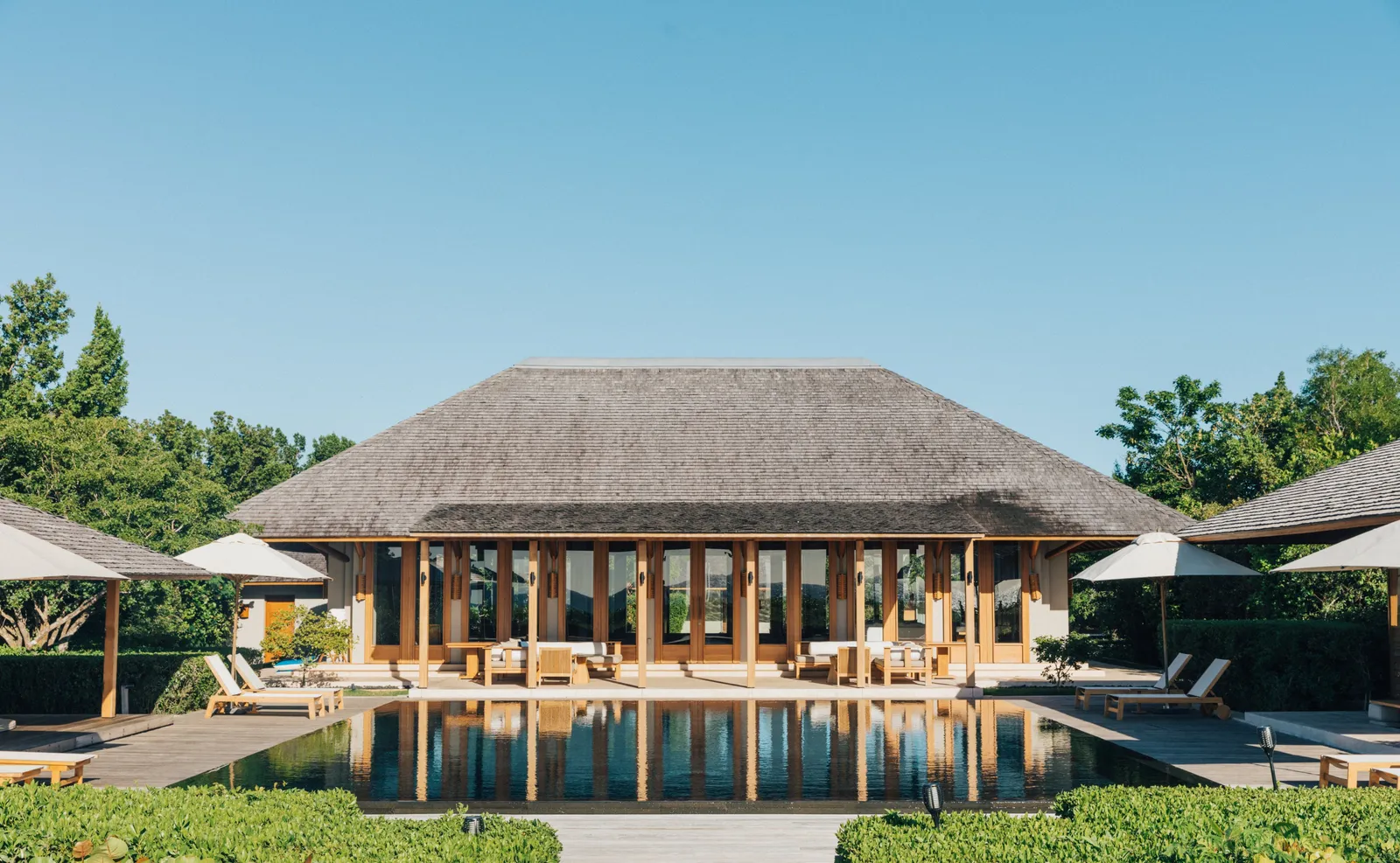 A Beach Sala Villa’s central pavilion, open on every side, beyond the infinity pool and parasols.