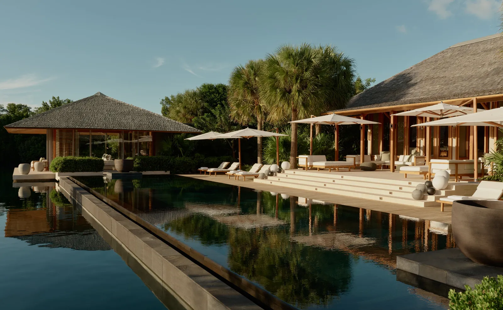 The 4-bedroom Serenity Villa: the infinity pool, stone steps and pavilions with palms behind.