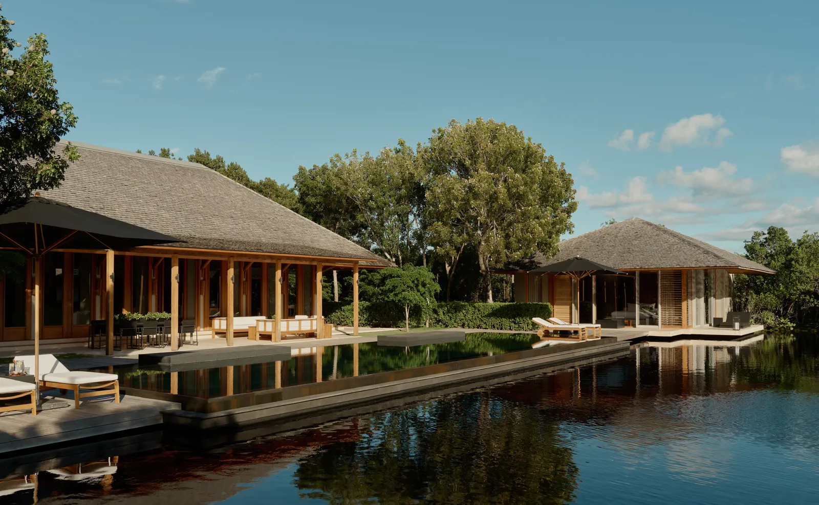 A 3-bedroom villa: shingle-roofed pavilions round the dark pool, loungers at its edge.
