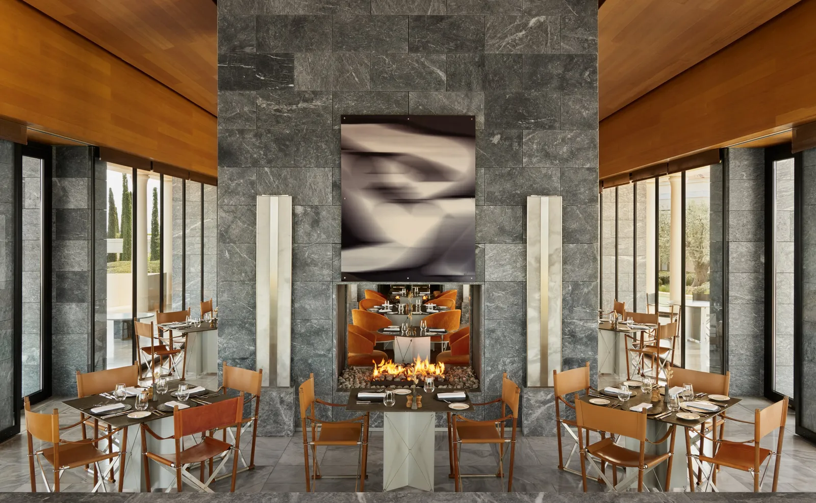 The restaurant: tables with leather chairs round a lit fireplace set in a grey marble wall, under a timber ceiling.