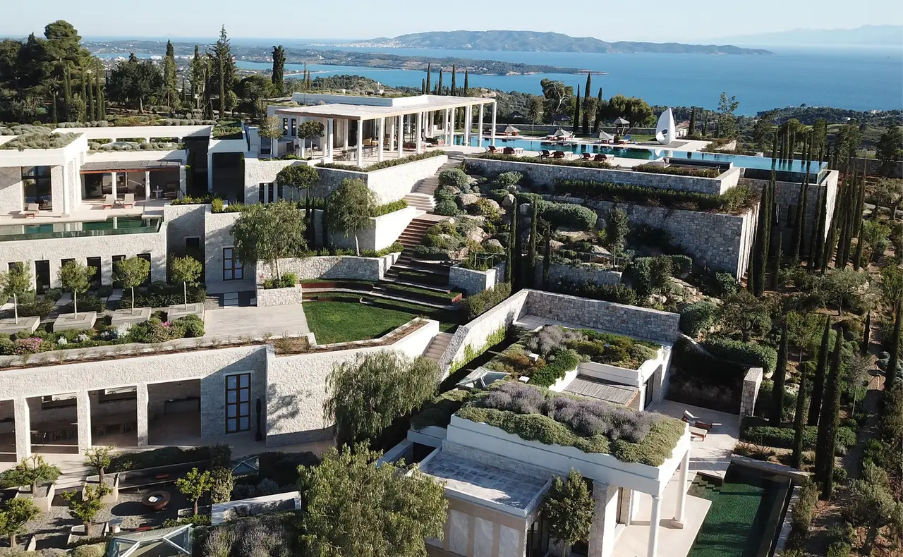 Villa 20 from above: terraces on several levels, roof gardens, a colonnaded portico, an infinity pool and the sea with an island on the horizon.