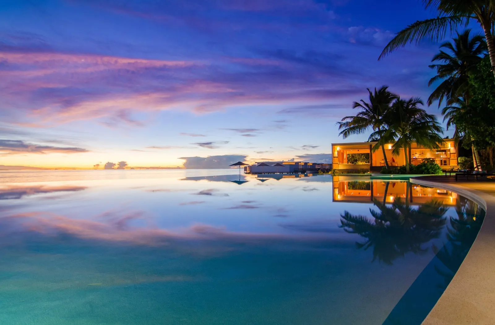 An overwater-villa pool at dusk
