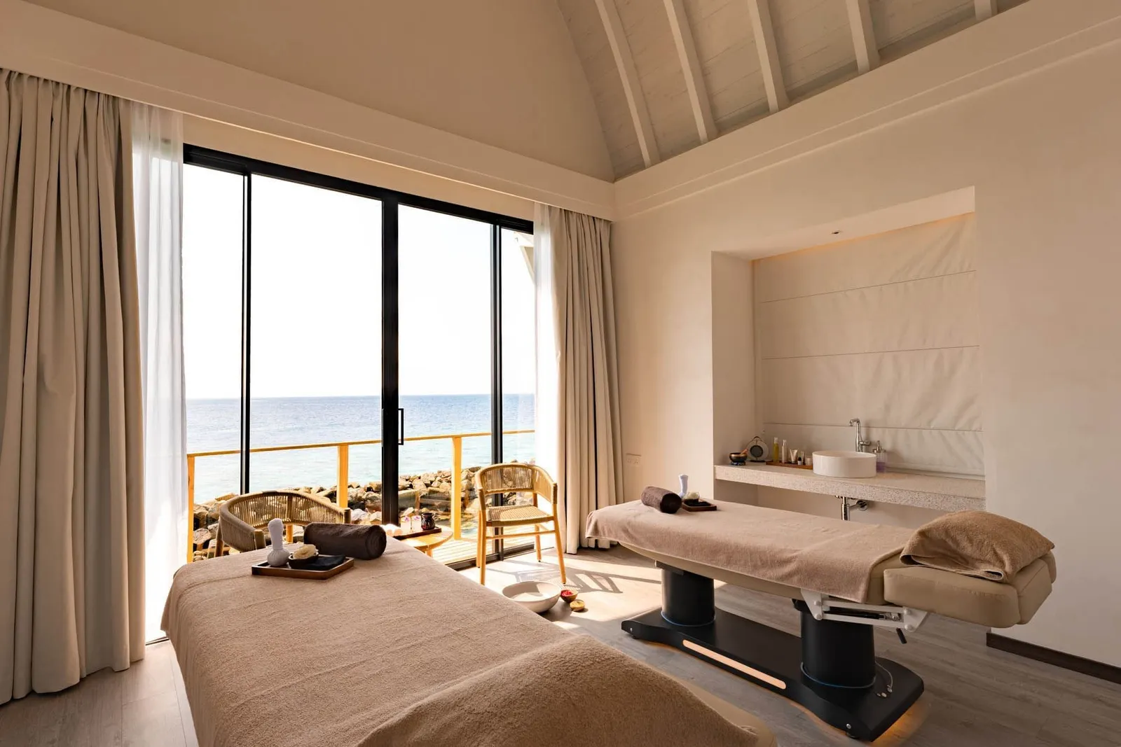 A treatment room for 2 at Kandu Spa, its glass wall open to the sea.